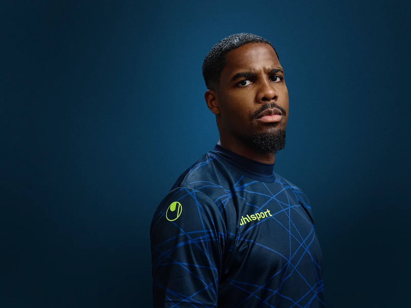 Mike Maignan im uhlsport-Trikot vor dunkelblauem Studiohintergrund