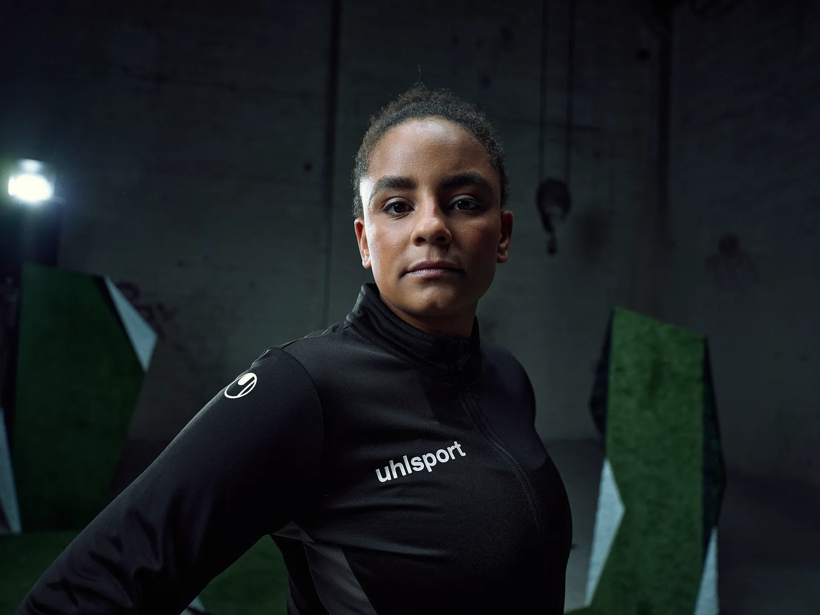 Spielerin in schwarzer Trainingsjacke, dunkle Halle